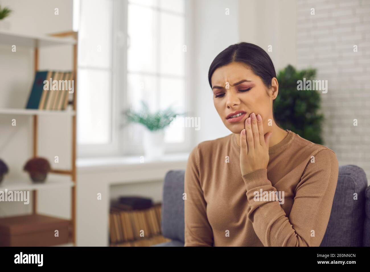 Donna che soffre di mal di denti o sensibilità dei denti e guancia toccante con dolore Foto Stock