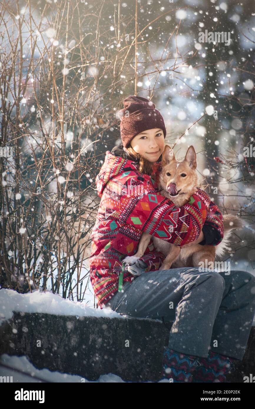 la ragazza teen abbraccia il suo cane all'aperto in inverno Foto Stock