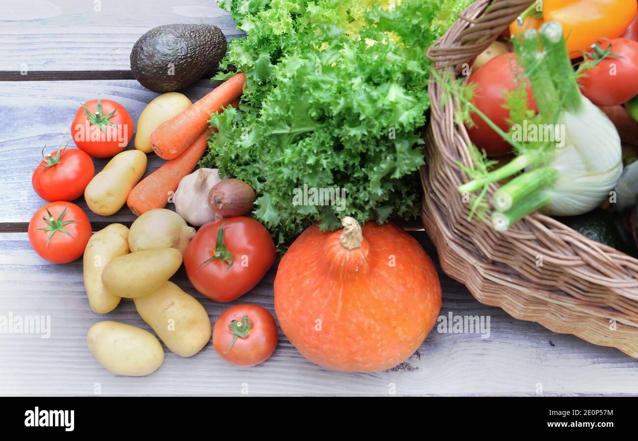 verdure varie e colorate messe su un tavolo accanto a. un cestino Foto Stock