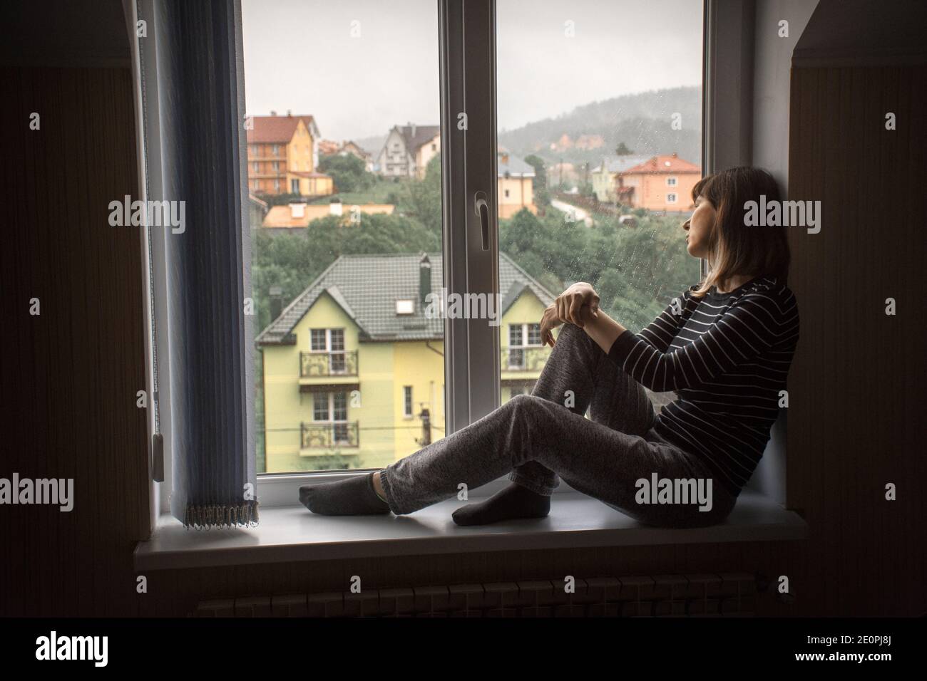 la ragazza da sola si siede a casa accanto alla finestra Foto Stock