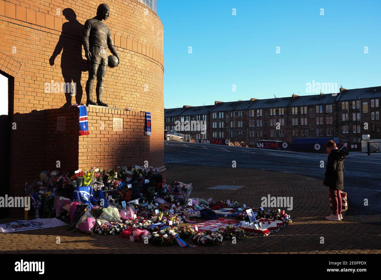 Glasgow, Regno Unito, 2 gennaio 2021. Sostenitori del Rangers Football Club Lascia fiori e sciarpe in un memoriale (raffigurante il calciatore dei Rangers John Greig) a quei 66 tifosi che hanno perso la vita nello Ibrox Stadium disasterwhichc è accaduto 50 anni fa oggi il 2 gennaio 1971. L'anniversario cade nel giorno in cui il Rangers FC gioca i loro rivali Celtic FC, a casa, in una partita di campionato. Foto: Jeremy Sutton-Hibbert/Alamy Live News. Foto Stock