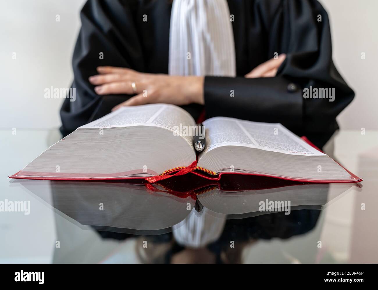 Giustizia, avvocato donna che tiene e legge libro aperto di legge rossa - diritto francese Foto Stock
