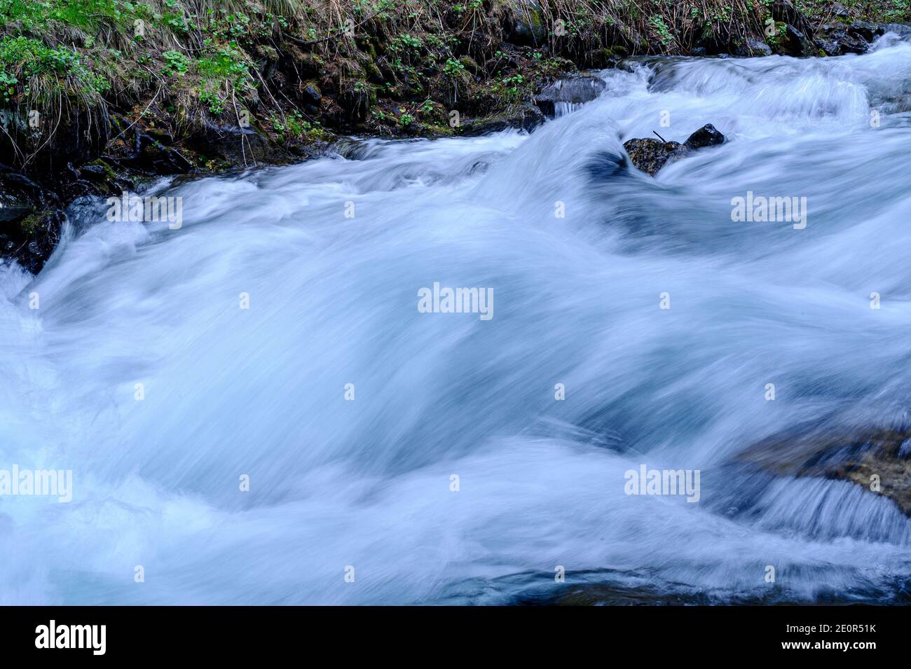 Primo piano sull'acqua di un torrente che scorre su rocce nelle Hautes-Alpes. Un effetto di sfocatura del movimento si ottiene con una regolazione lenta dell'otturatore. Foto Stock