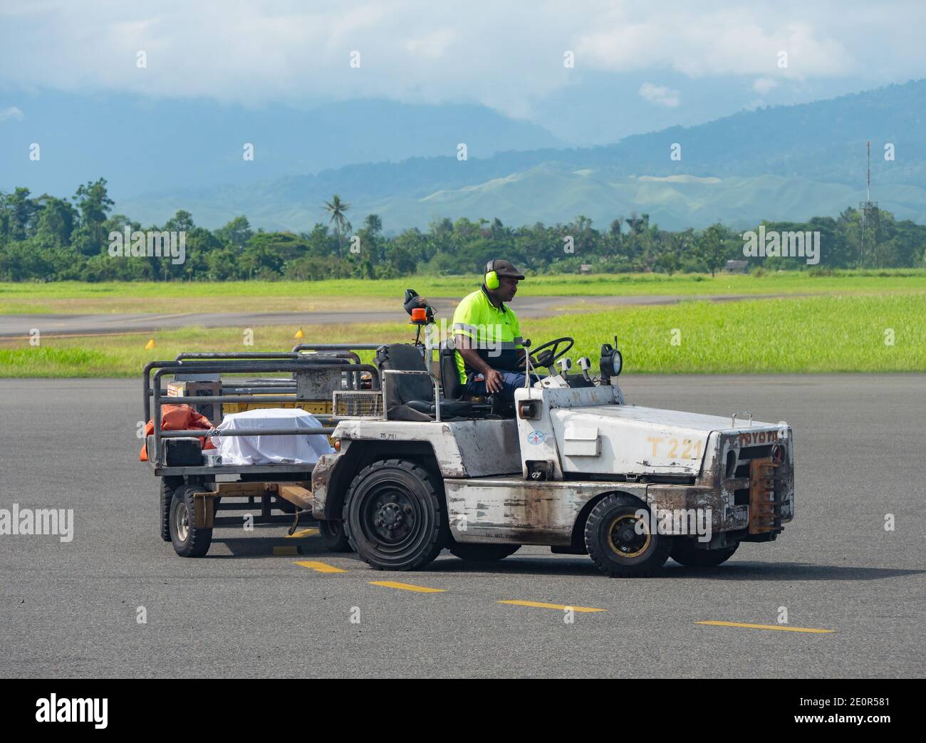 Il gestore di bagagli attende un volo per arrivare all'aeroporto di Nadzab in Lae, la capitale della provincia di Morobe e la seconda città più grande di Papua Nuova Guine Foto Stock
