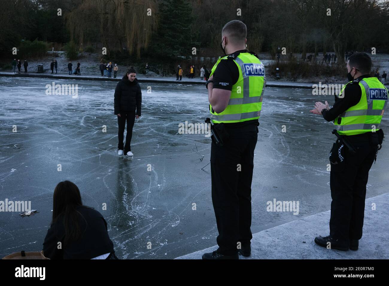 Glasgow, Regno Unito, 2 gennaio 2021. Le persone approfittano della stagione fredda per pattinare sul ghiaccio e camminano sul laghetto delle barche ghiacciate nel Queen's Park, nel lato sud della città. La polizia alla fine ha rimosso tutti dal ghiaccio a causa di preoccupazioni per la sicurezza. Foto: Jeremy Sutton-Hibbert/ Alamy Live News Foto Stock