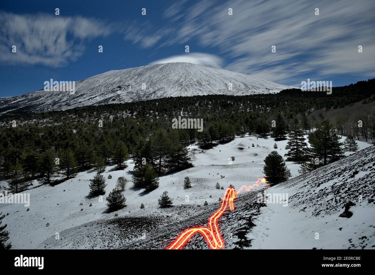 paesaggio al chiaro di luna con sentieri luminosi e nuvole in movimento a lungo Esposizione sull'Etna innevata nella notte della Sicilia in inverno un punto di riferimento della natura tour Foto Stock