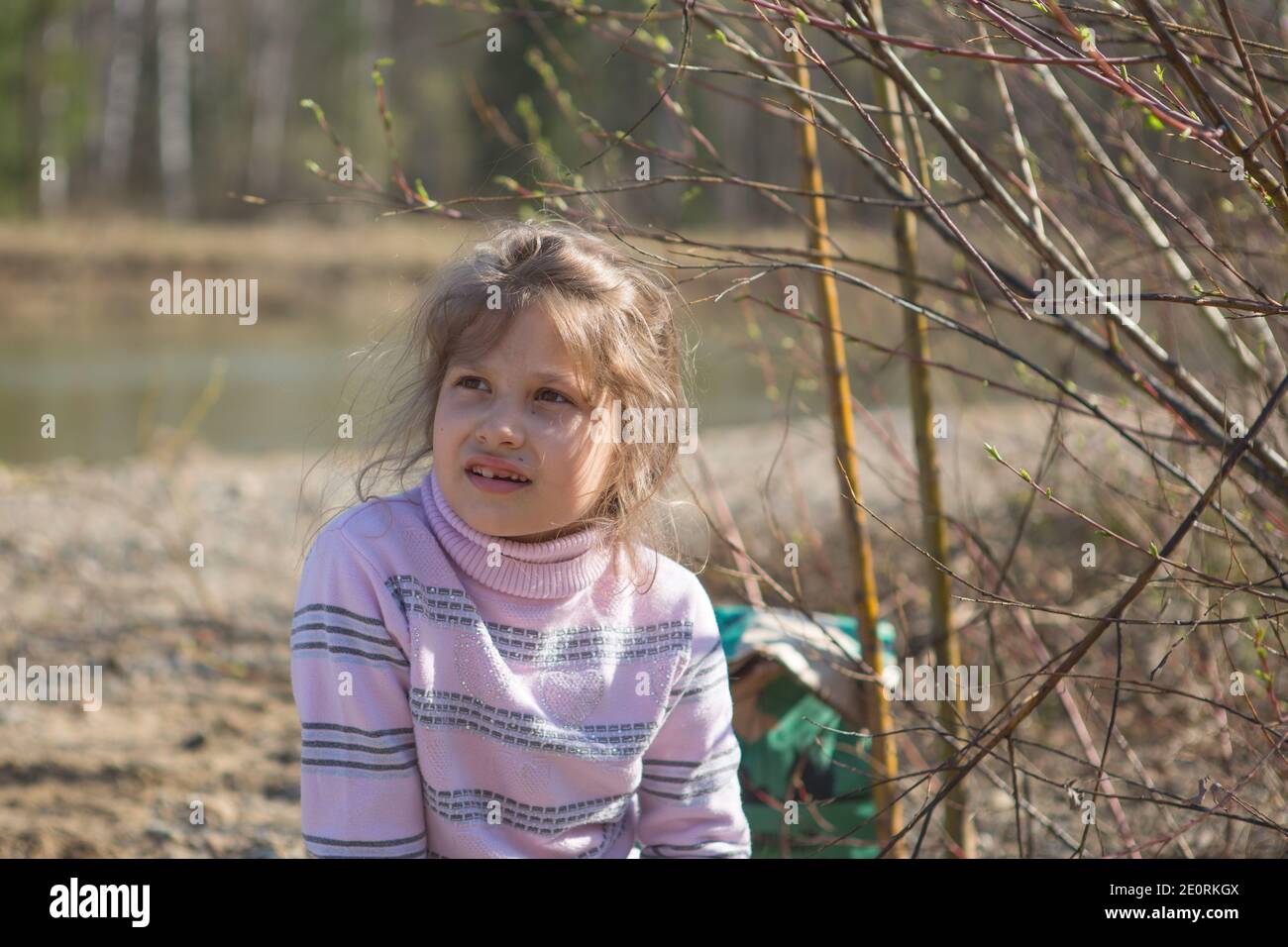 Una bambina bionda guarda attentamente in lontananza. Foto Stock