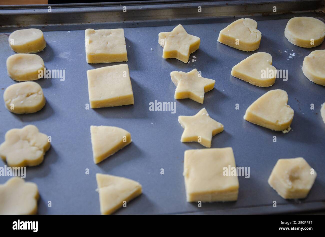 Biscotti shortbread tagliati in forme diverse e disposti ordinatamente su una pecora da forno pronta a cucinare nel over. Foto Stock