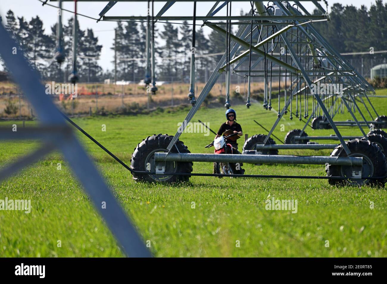 Un agricoltore su una motocicletta controlla le sue attrezzature di irrigazione a Canterbury, Nuova Zelanda Foto Stock