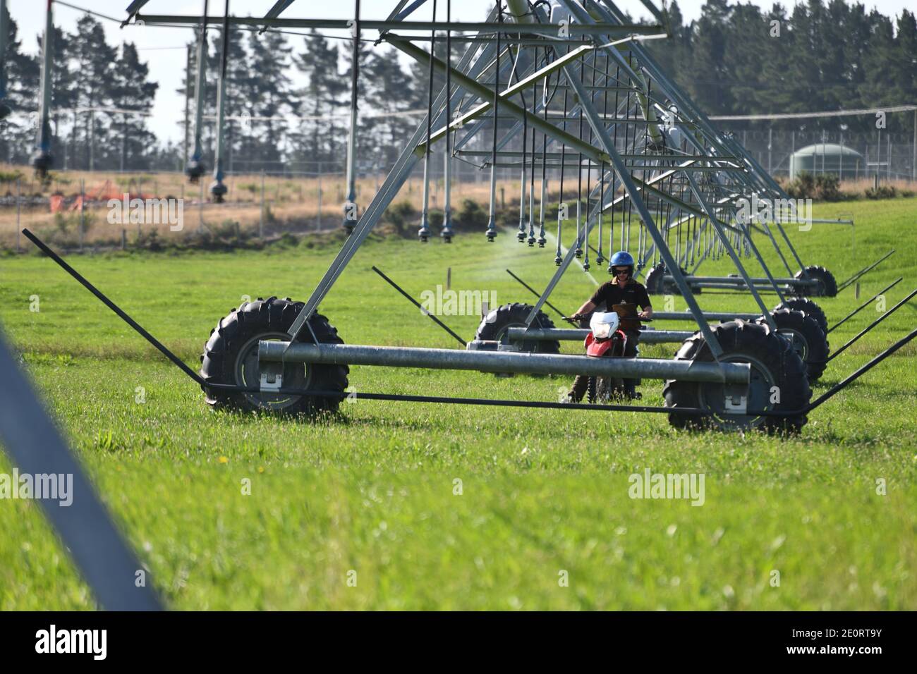 Un agricoltore su una motocicletta controlla le sue attrezzature di irrigazione a Canterbury, Nuova Zelanda Foto Stock