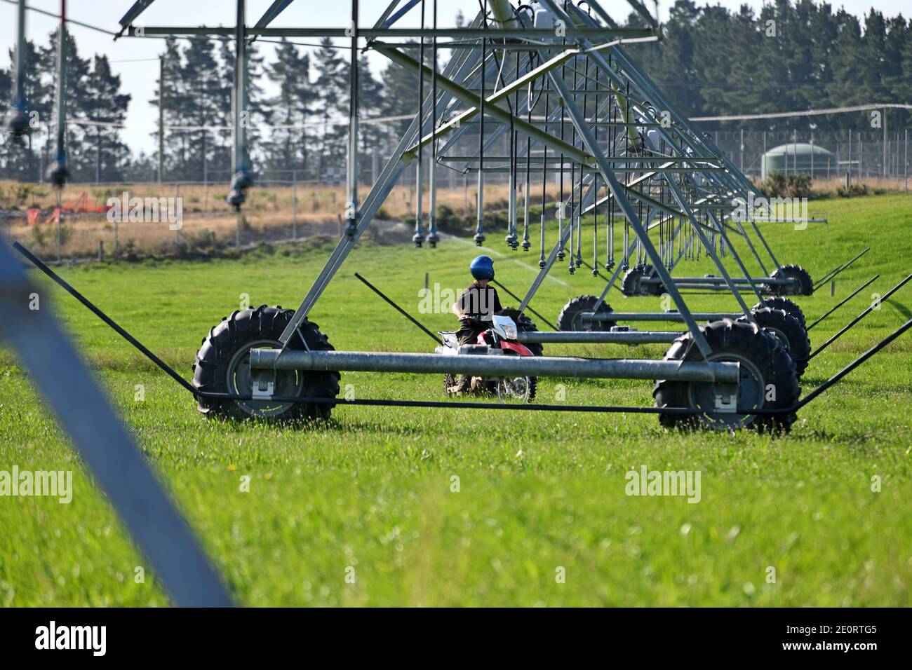 Un agricoltore su una motocicletta controlla le sue attrezzature di irrigazione a Canterbury, Nuova Zelanda Foto Stock