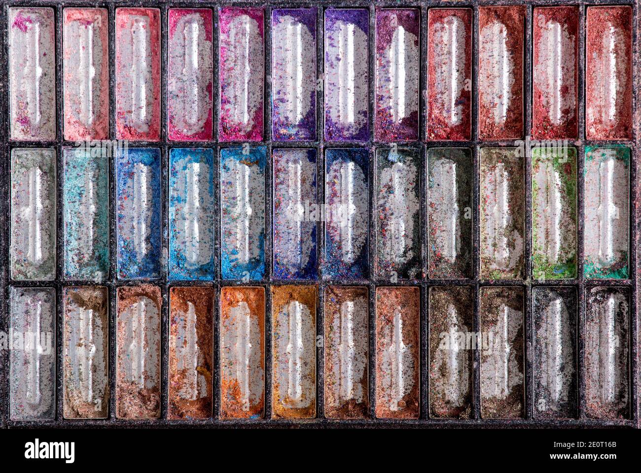 Vista piatta del contenitore della tavolozza dell'ombra dell'occhio vuota rotto con molti colori. Concetto astratto di sfondo. Foto Stock