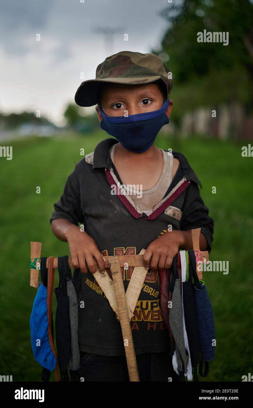 Durante la chiusura del COVID - 19, Ramzan, un bambino di 9 anni, vende maschere facciali che la madre cucì a casa, sulle strade di Islamabad, la capitale del Pakistan. Foto Stock