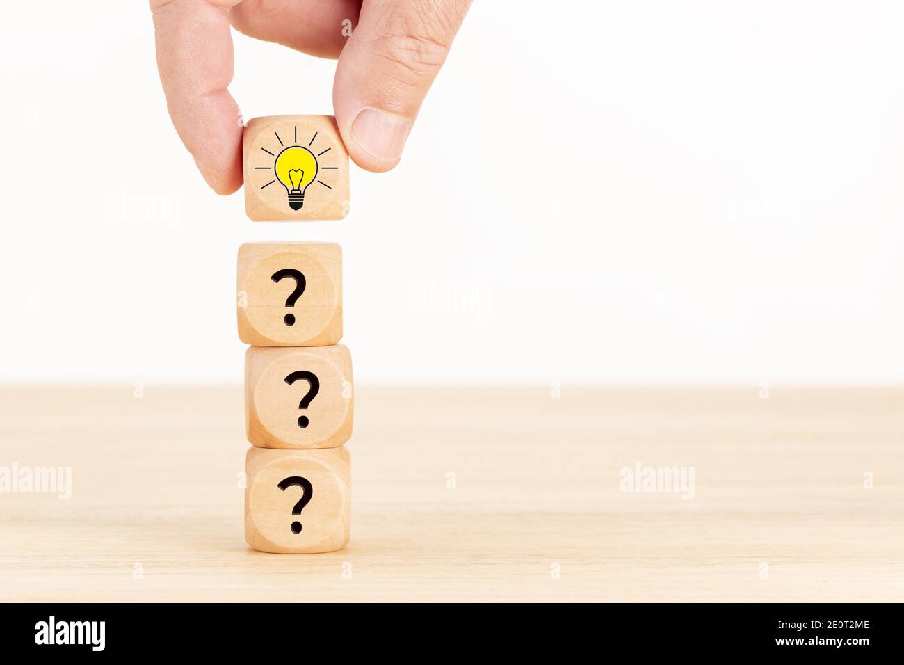 Idea creativa o concetto di innovazione. Blocco cubo di legno selezionato a mano con il simbolo del punto interrogativo e l'icona della lampadina. Spazio di copia Foto Stock