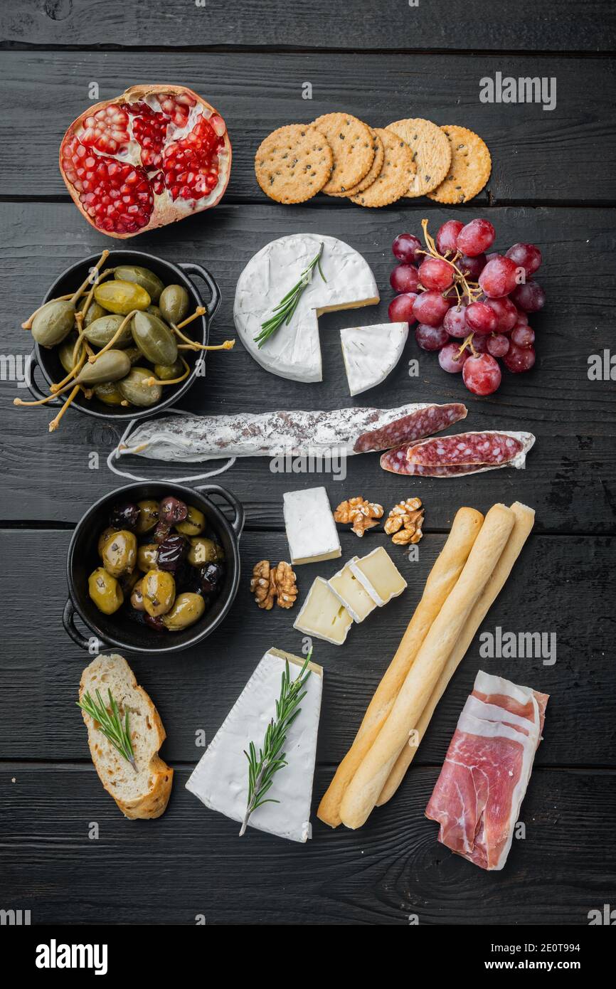 Tavolo per antipasti con diversi antipasti, su tavolo in legno nero, piatto Foto Stock