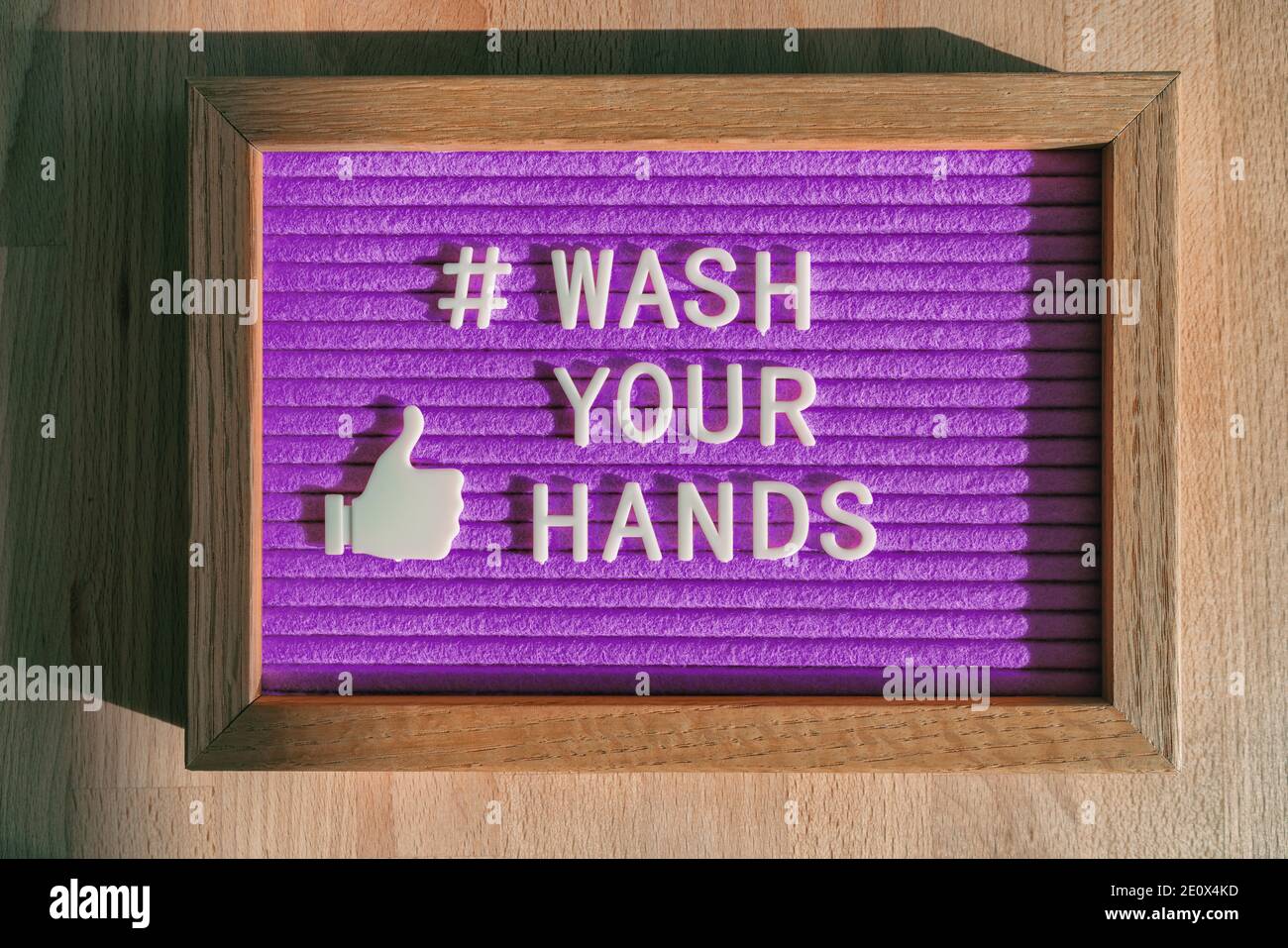 Lavare le mani hashtag messaggio sul cartellone viola avviso presso il negozio di affari buona igiene delle mani per la prevenzione del coronavirus. Segnale di feltro per i social media Foto Stock