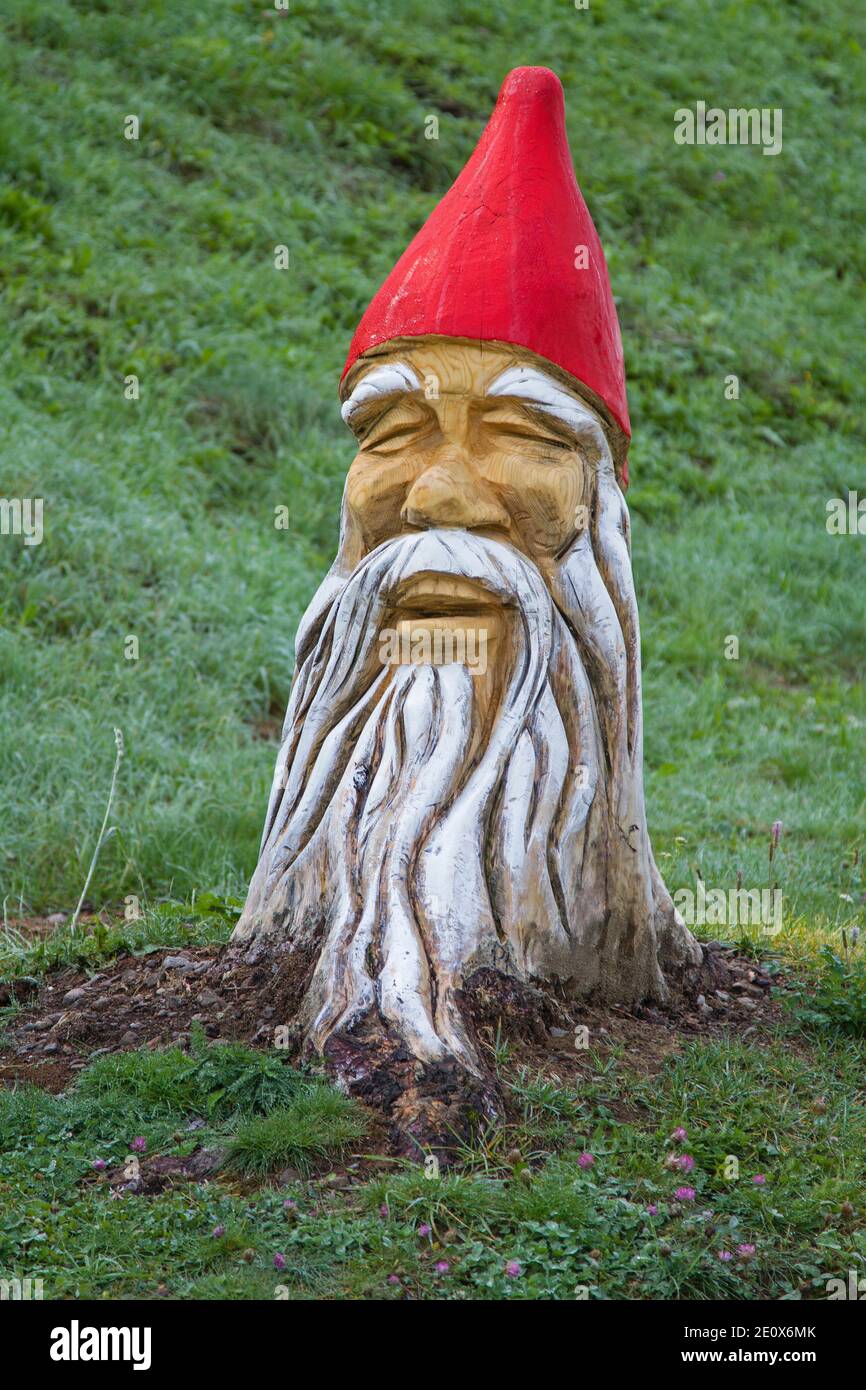 Trunks di albero fantasiosamente processati e verniciati nella forma di Nani stare sul lato del percorso Foto Stock