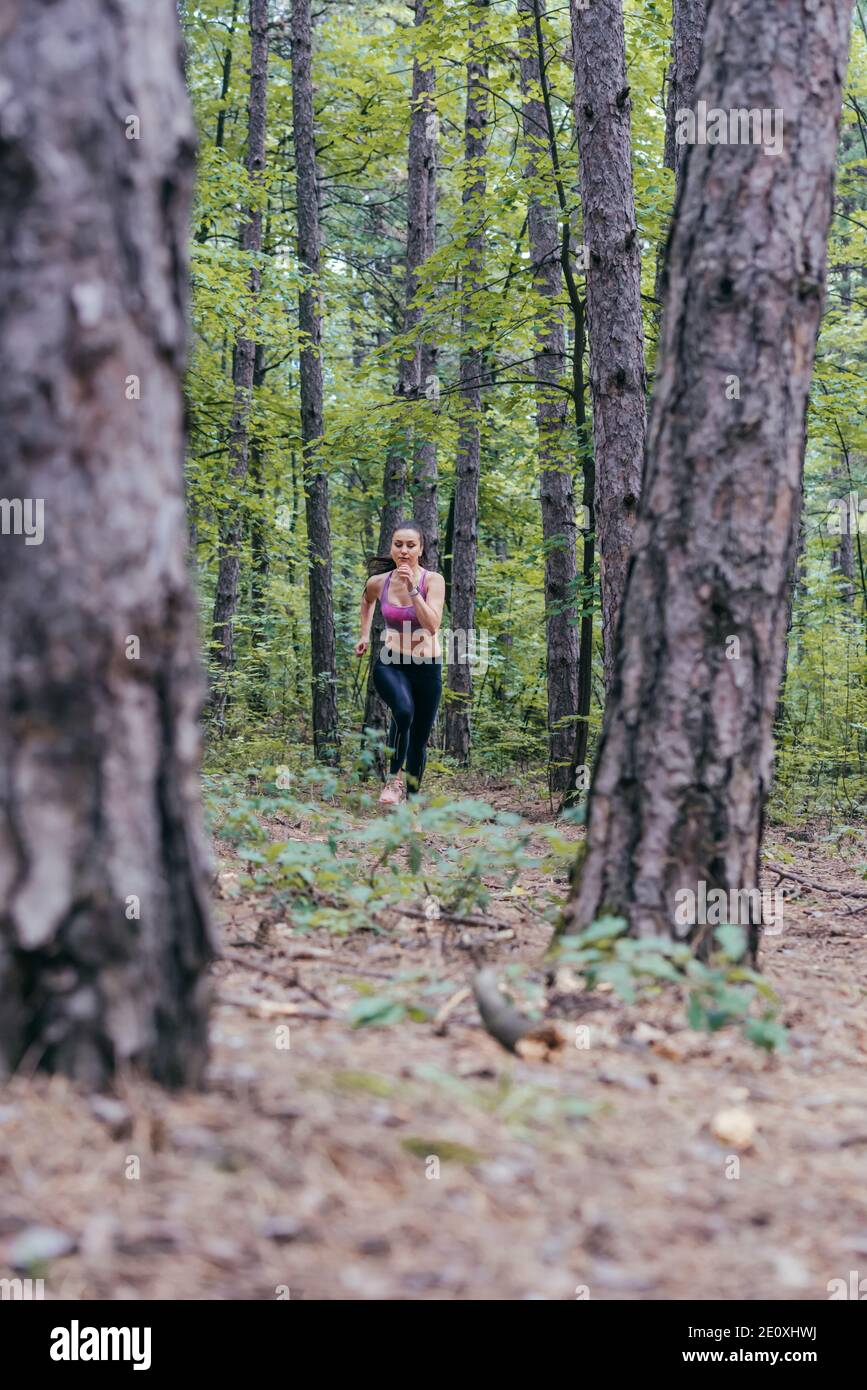 Giovane caucasica ragazza jogging nella foresta visto da lontano. Foto Stock
