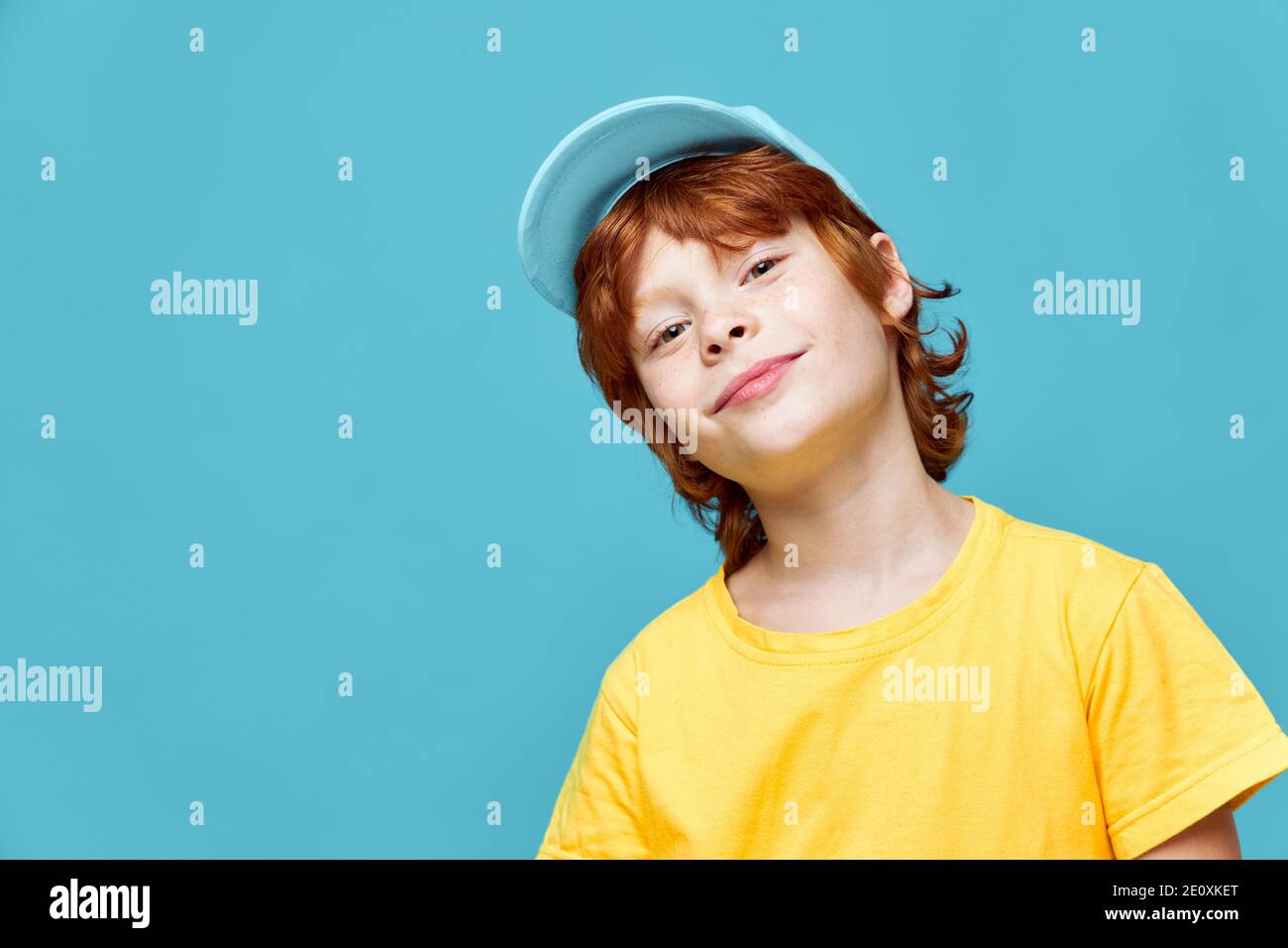 ritratto di una testa di ragazzo dai capelli rossi inclinata su un lato Spazio di copia con tappo blu Foto Stock