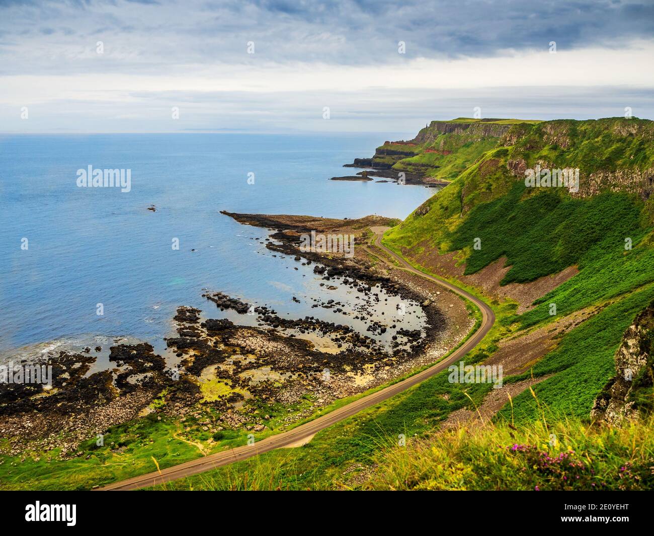 Costa atlantica, Irlanda del Nord, Regno Unito. Scogliere con strati geologici e vista lontano Selciato del Gigante, formazioni geologiche naturali uniche del vulcanico b Foto Stock