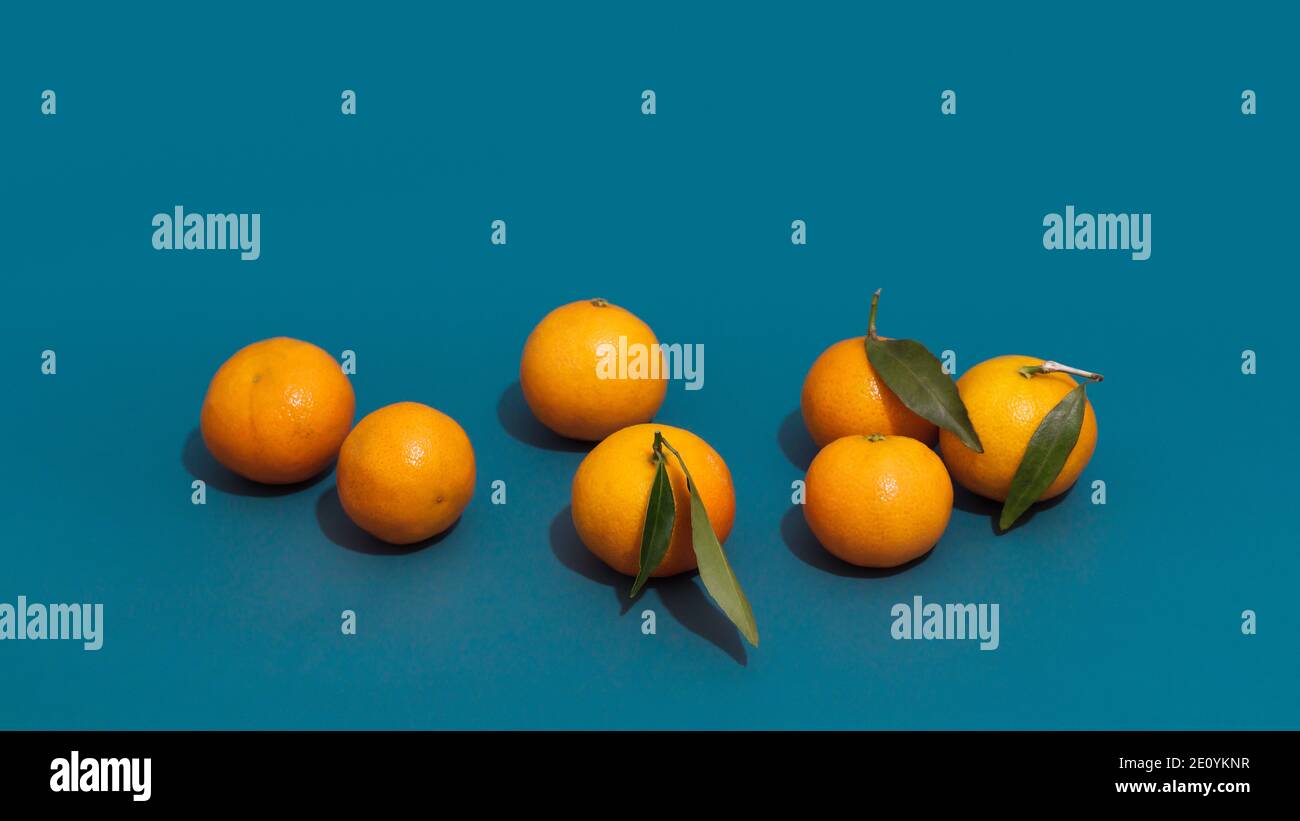 Clementine frutta con foglie verdi, primo piano. Composizione di frutta minimalistica con mandarini e ombre acute. Foto Stock