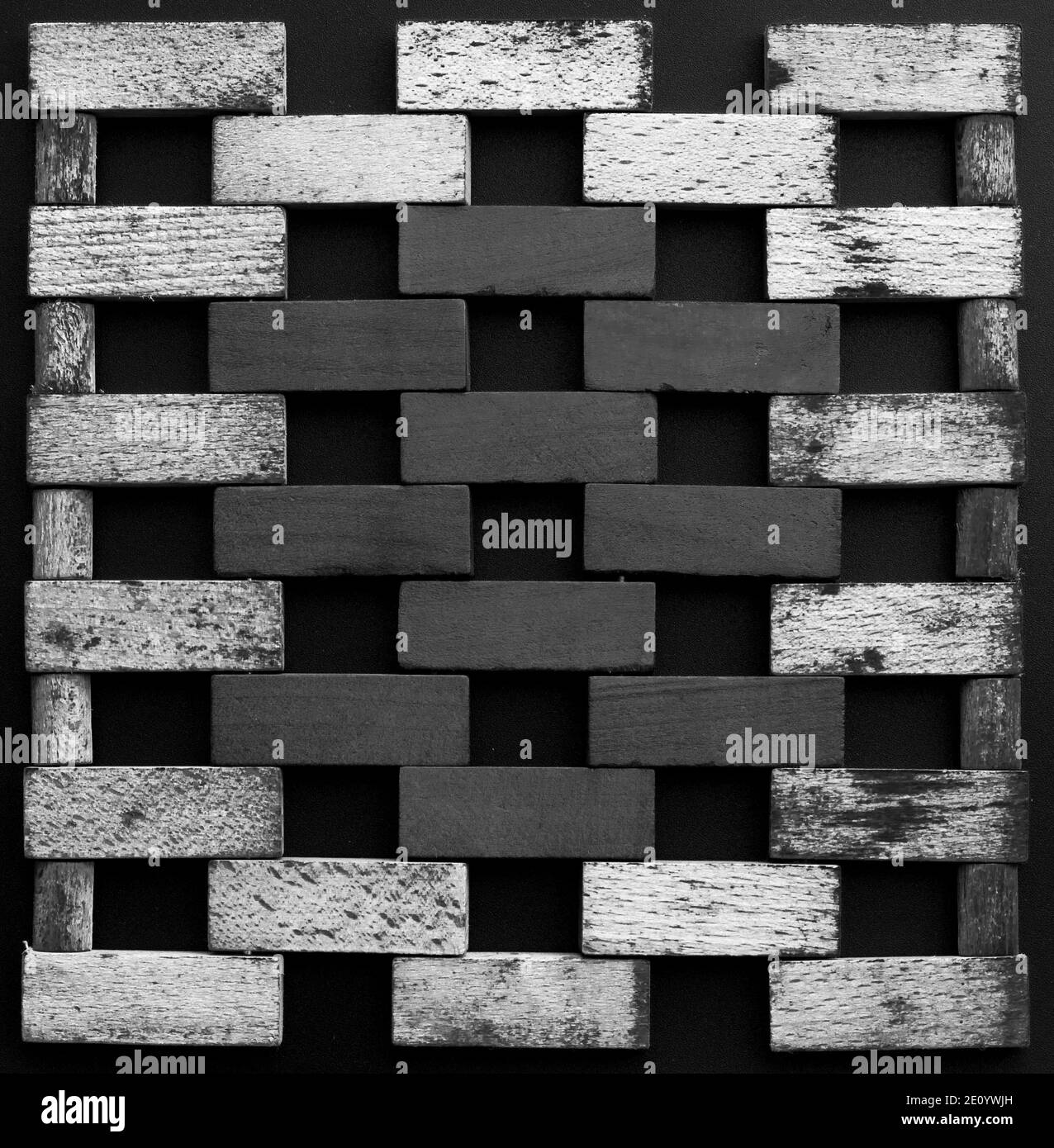 Muro fatto di piccoli mattoni di legno. Blocchi di legno bianco e nero che assomigliano a una parete di mattoni su sfondo nero. Texture. Sfondo. Foto Stock