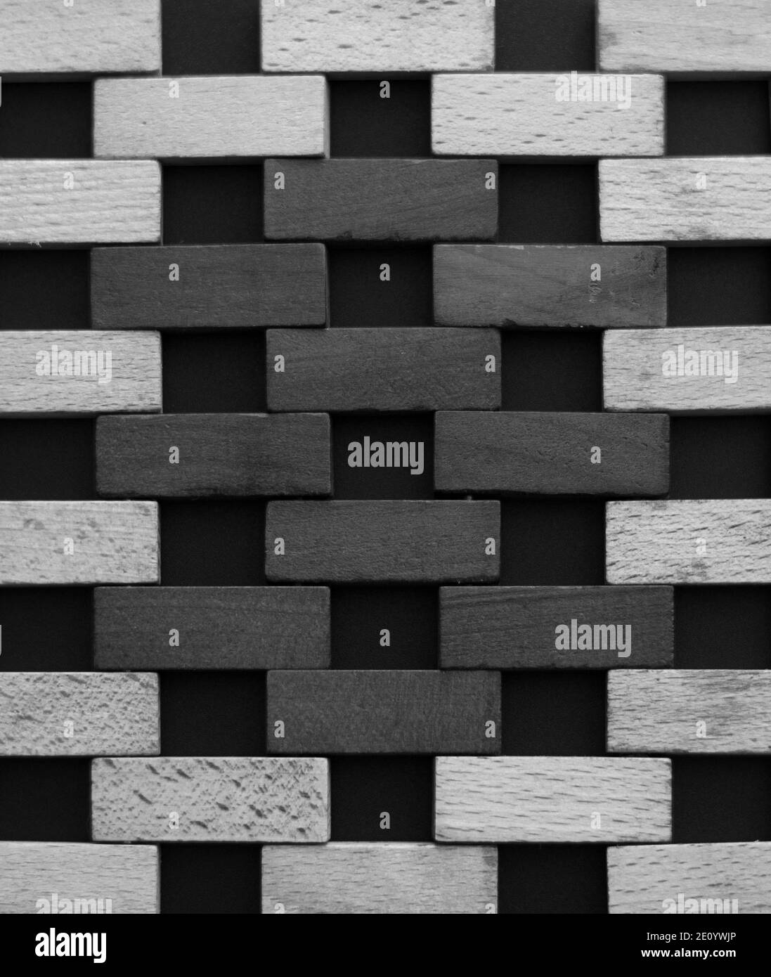 Muro fatto di piccoli mattoni di legno. Blocchi di legno bianco e nero che assomigliano a una parete di mattoni su sfondo nero. Texture. Sfondo. Foto Stock
