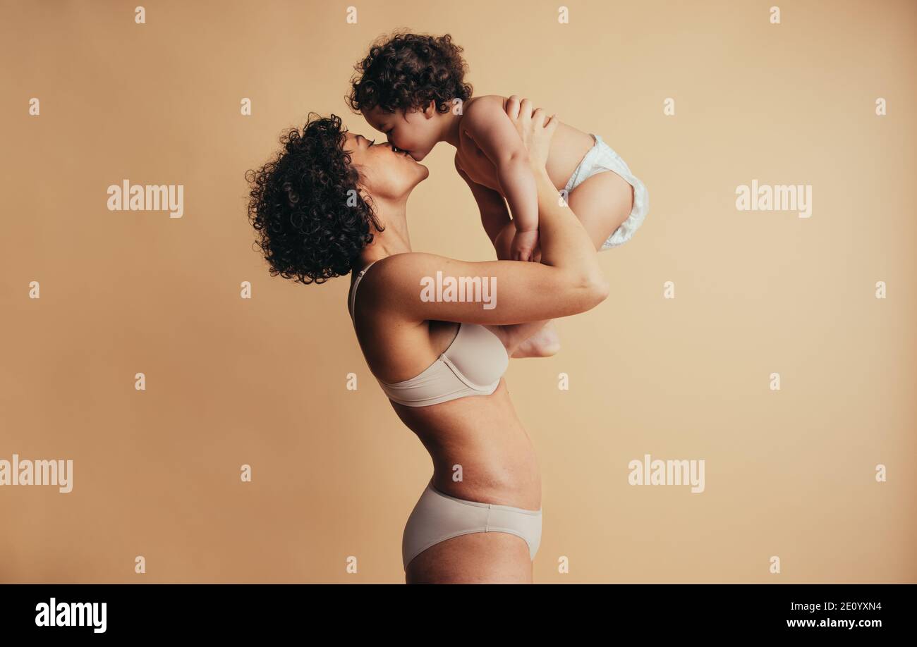 Donna che tiene il suo bambino e baciando il giorno delle madri. Madre che ama il suo bambino. Foto Stock