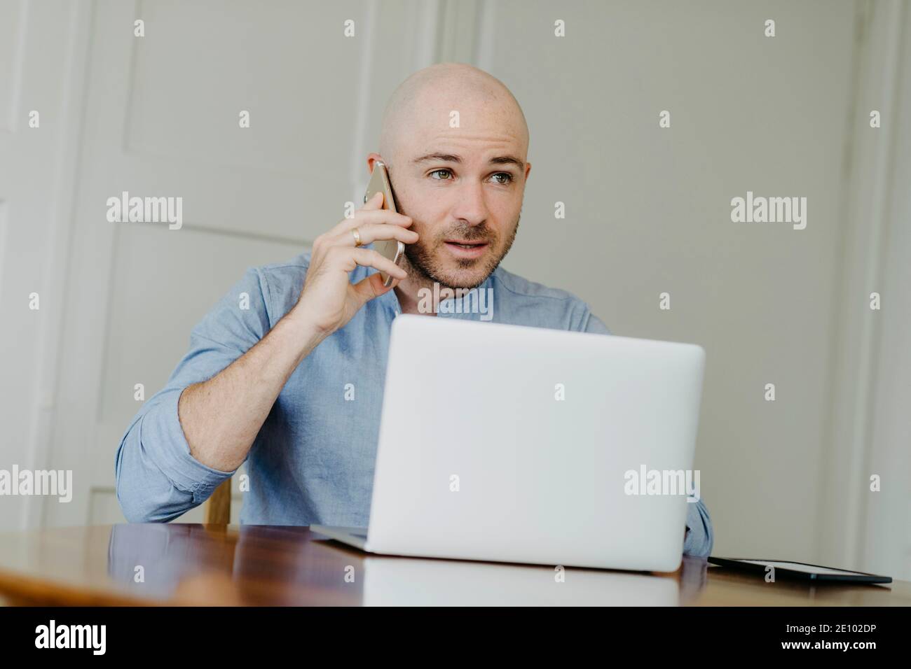 L'uomo lavora su un computer portatile, effettua chiamate telefoniche con smartphone, ufficio domestico Foto Stock