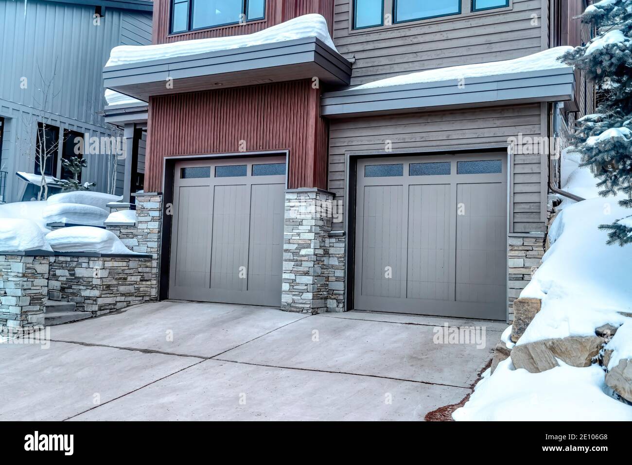 Due garage auto con porte in vetro grigio a pannelli presso il facciata di casa in inverno Foto Stock