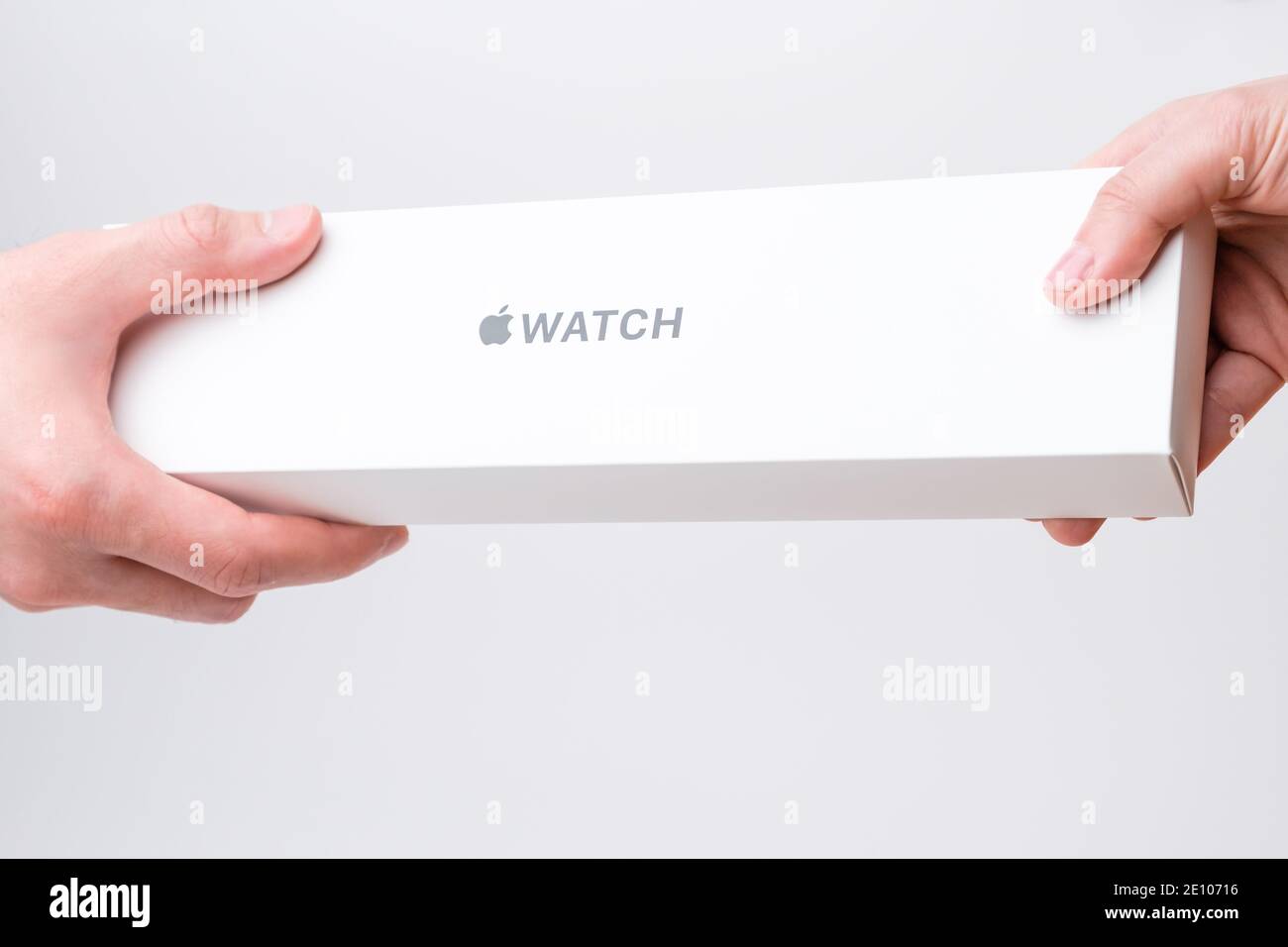 Mano uomo e donna che tiene una scatola con orologio Apple su sfondo grigio, dicembre 2020, San Francisco, Stati Uniti Foto Stock