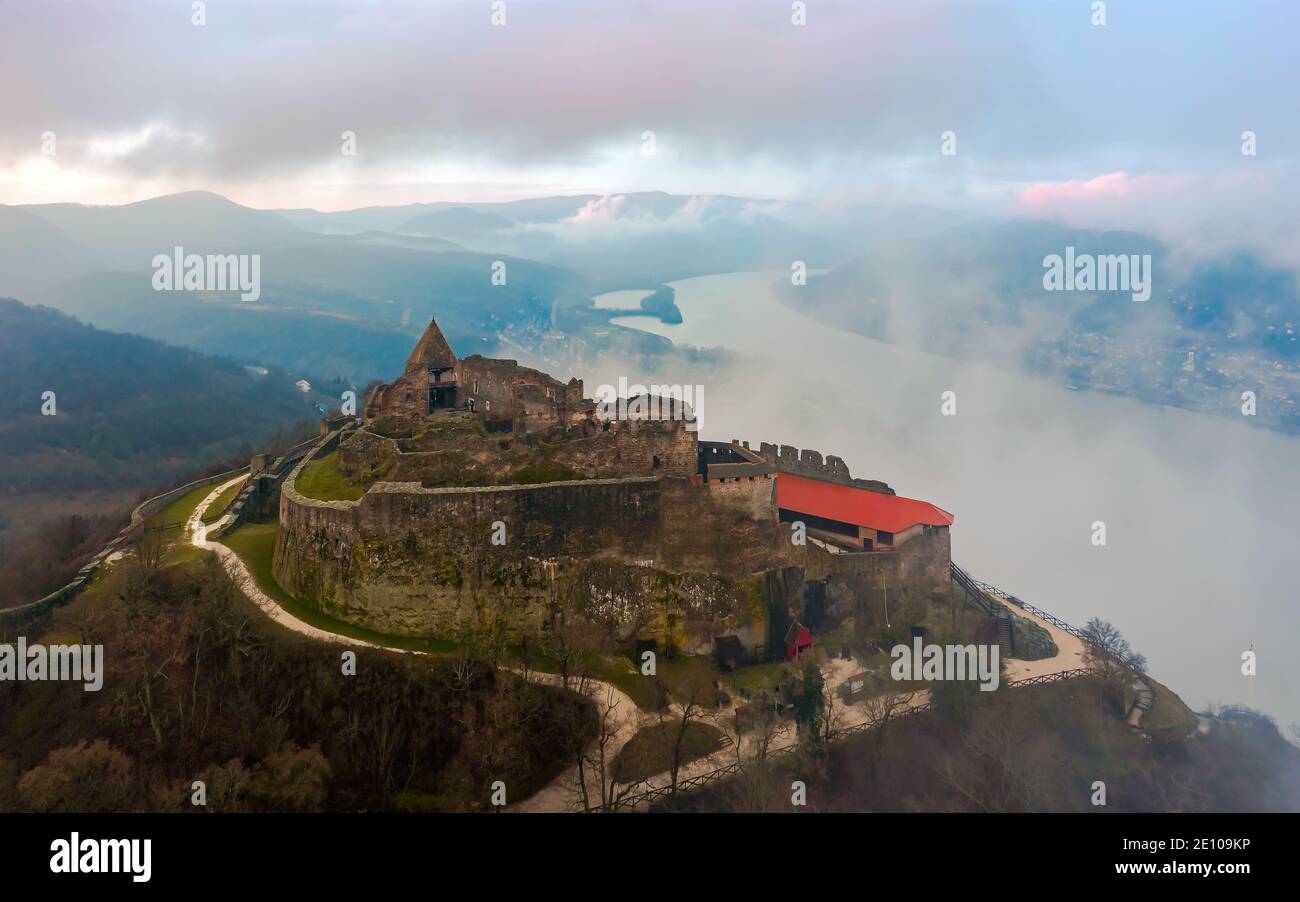 Rovine del castello della cittadella di Visegrad nel Danubio curva Ungheria. Fantastico paesaggio aereo in cattive condizioni atmosferiche. Nebbia, alba nuvolosa Foto Stock