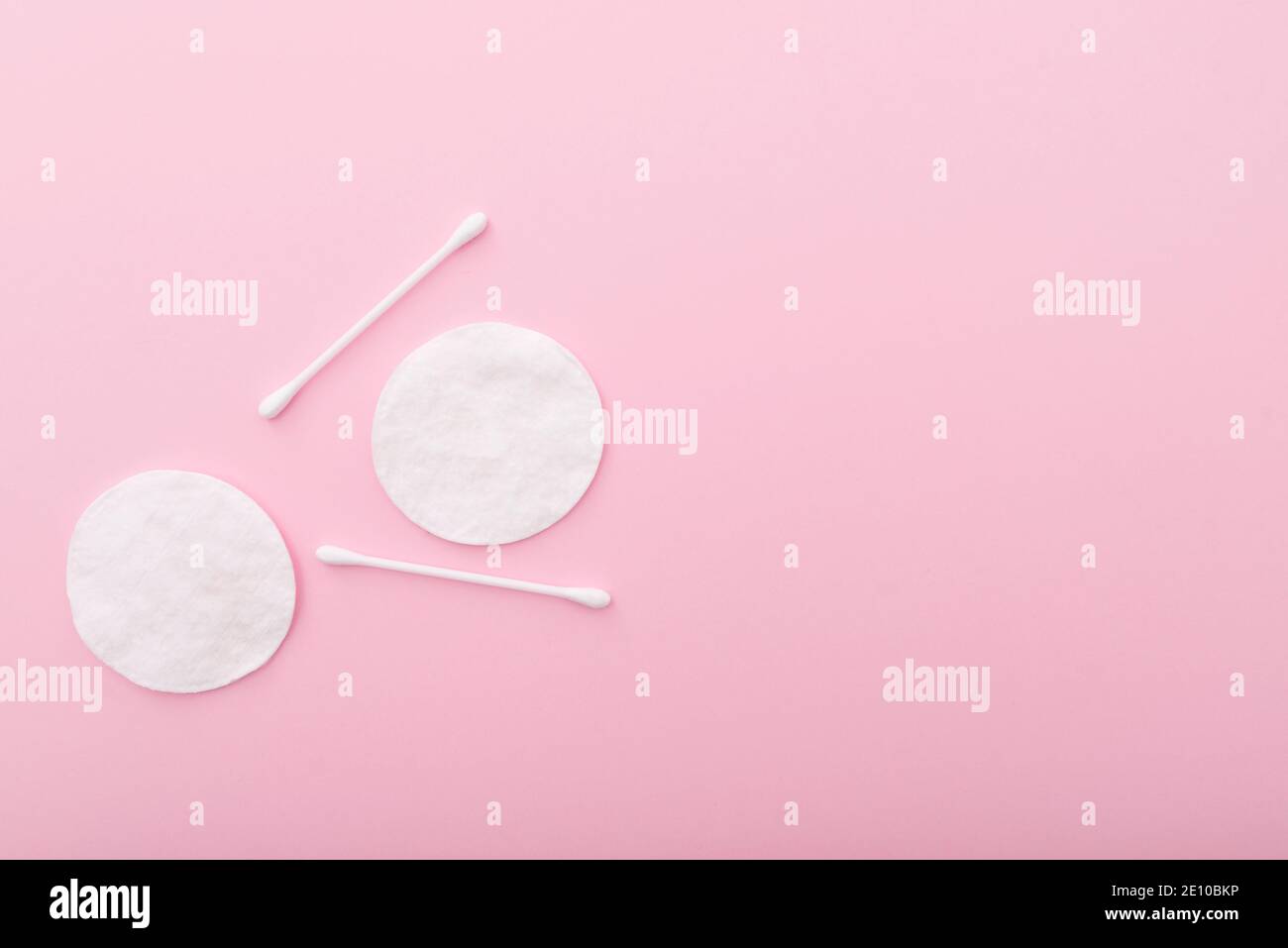 Spugne di cotone con bastoncini di cotone su sfondo rosa, con spazio per il testo Foto Stock