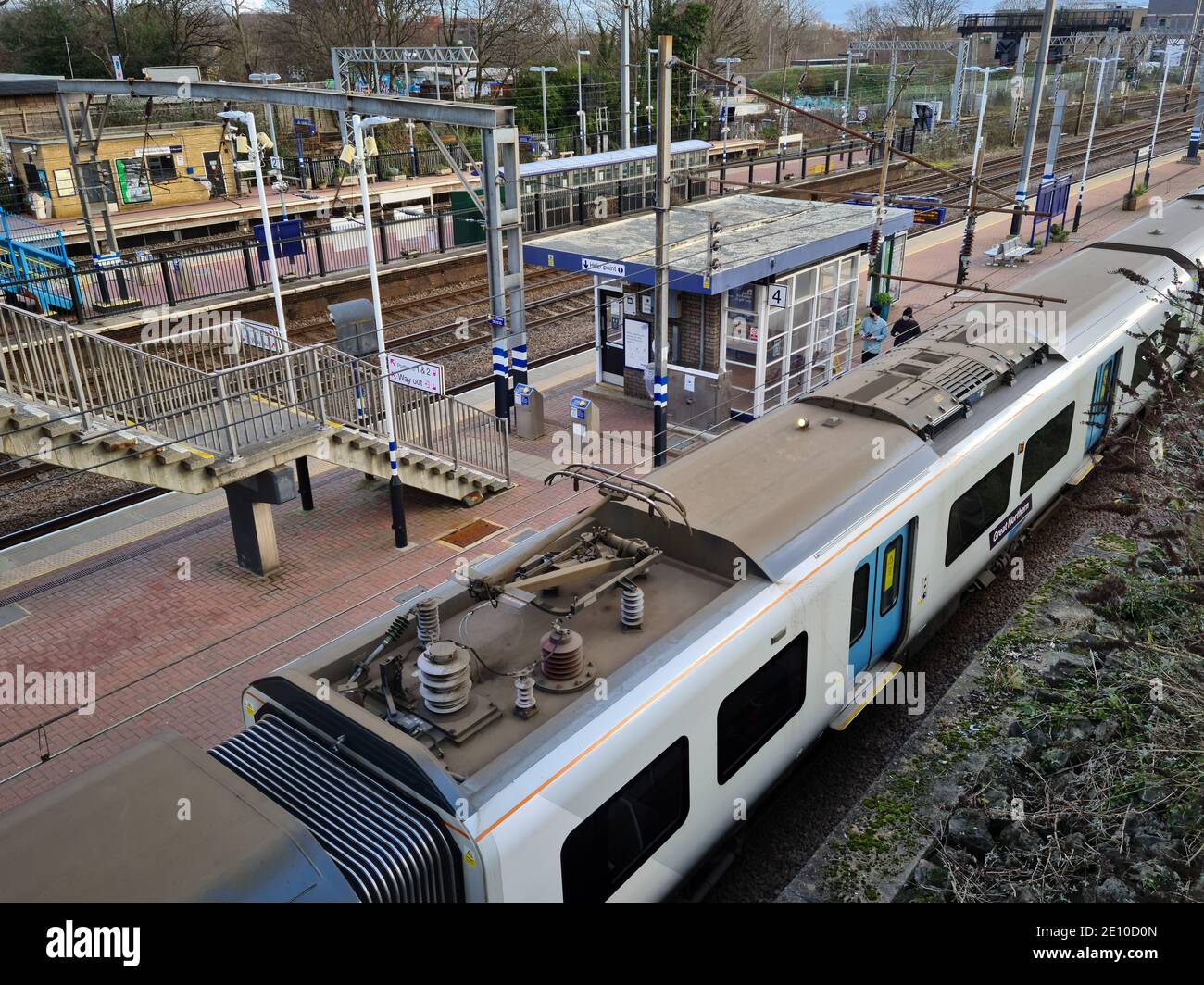 Una stazione ferroviaria suburbana con un treno in una piattaforma. Foto Stock
