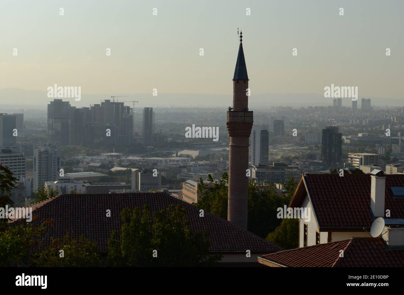 un minareto storico visibile attraverso le case Foto Stock