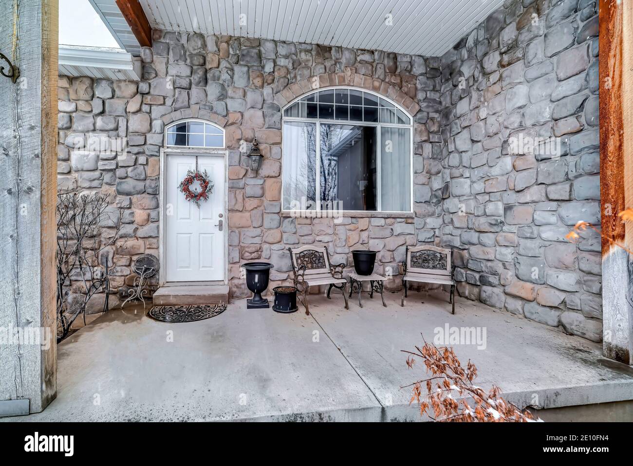 Home facciata con porta anteriore e finestra sullo specchio di poppa contro la pietra parete esterna Foto Stock