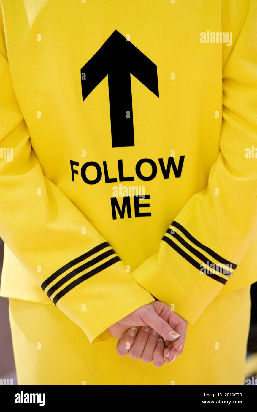 Frau mit einer gelben Uniform auf der 'Follow me' steht | Donna con una divisa gialla che dice 'Seguimi' Foto Stock