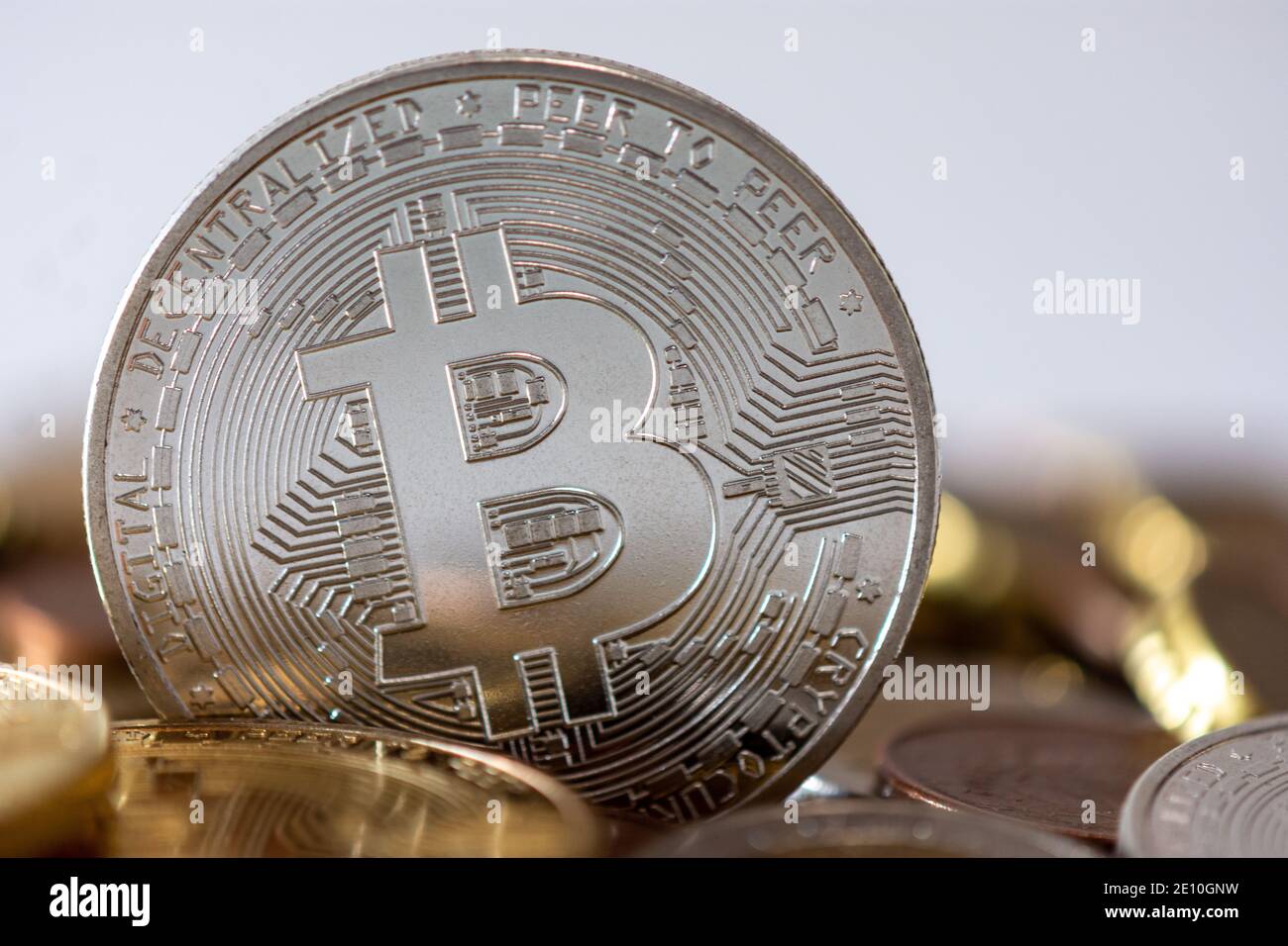 Una moneta d'argento in piedi tra molte monete offuscate. Bitcoin è una criptovaluta, una valuta digitale decentralizzata senza una banca centrale Foto Stock