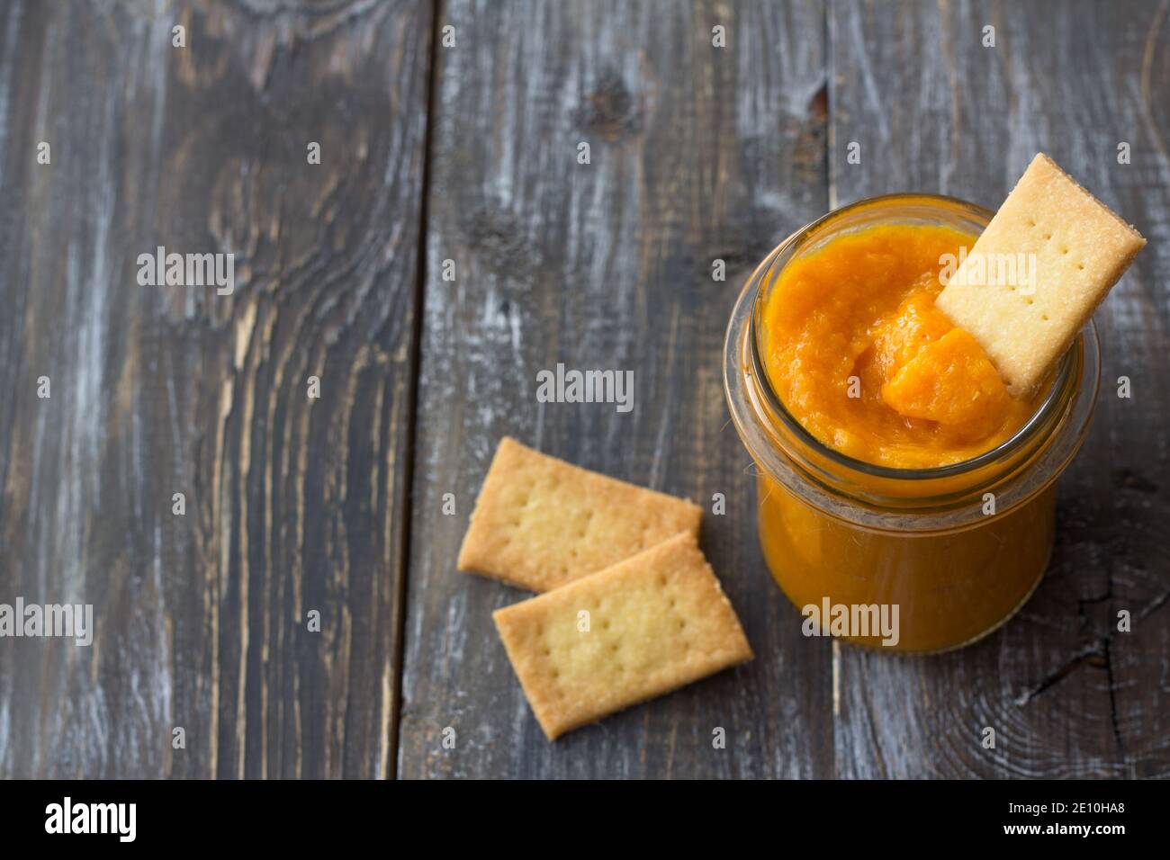 Marmellata d'arancia con albicocche secche su tavola di legno con biscotti. Dieta sana e cruda. Stile rustico. Fuoco selettivo. Spazio libero Foto Stock