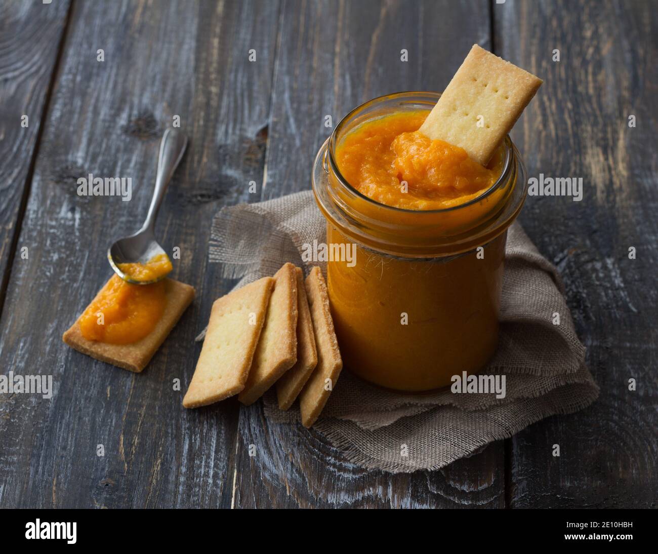 Confettura di arance crude sana con albicocche secche in un vaso di vetro con biscotti su un tavolo di legno. Dieta alimentare. Fuoco selettivo. Stile rustico Foto Stock