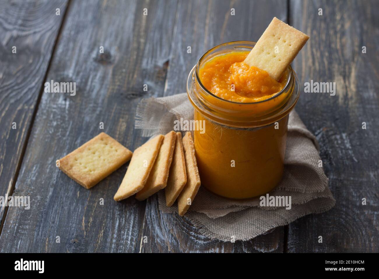 Confettura di arance crude sana con albicocche secche in un vaso di vetro con biscotti su un tavolo di legno. Dieta alimentare. Fuoco selettivo, spazio libero. Stile rustico Foto Stock