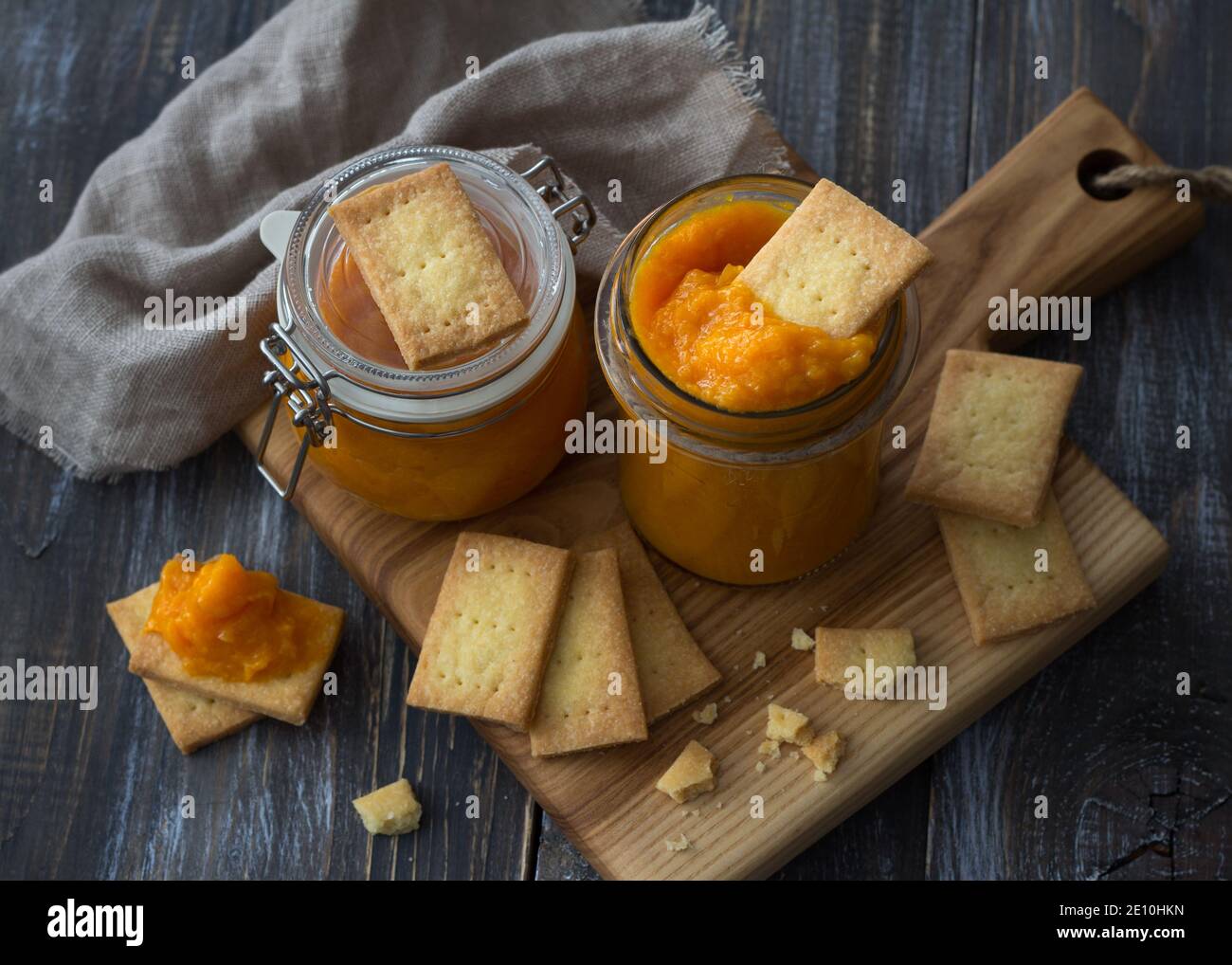 Confettura di arance crude sana con albicocche secche in un vaso di vetro con biscotti su un tavolo di legno. Dieta alimentare. Fuoco selettivo. Stile rustico Foto Stock