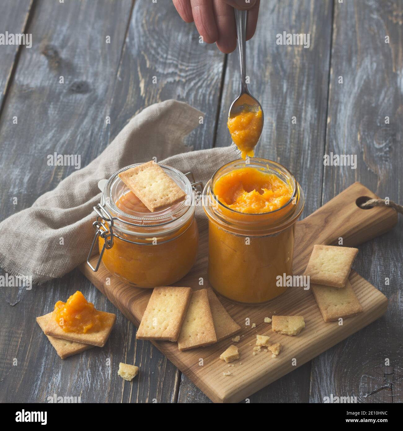Confettura di arance crude sana con albicocche secche in un vaso di vetro con biscotti su un tavolo di legno. Dieta alimentare. Fuoco selettivo. Stile rustico Foto Stock