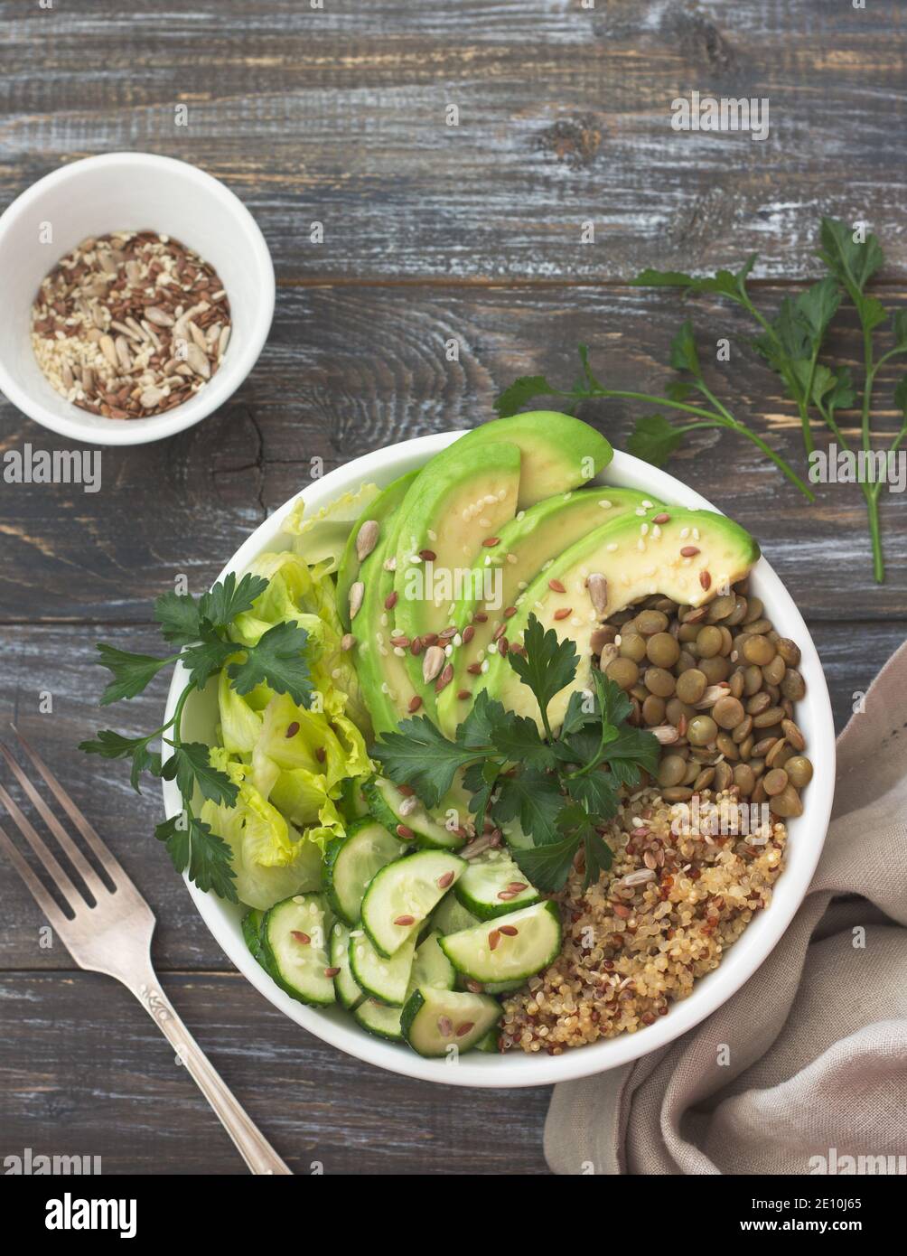 Coppa di Buddha verde con lenticchie, quinoa, avocado, cetriolo, lattuga fresca, erbe e semi. Cibo sano e salutare. Su sfondo di legno, Foto Stock