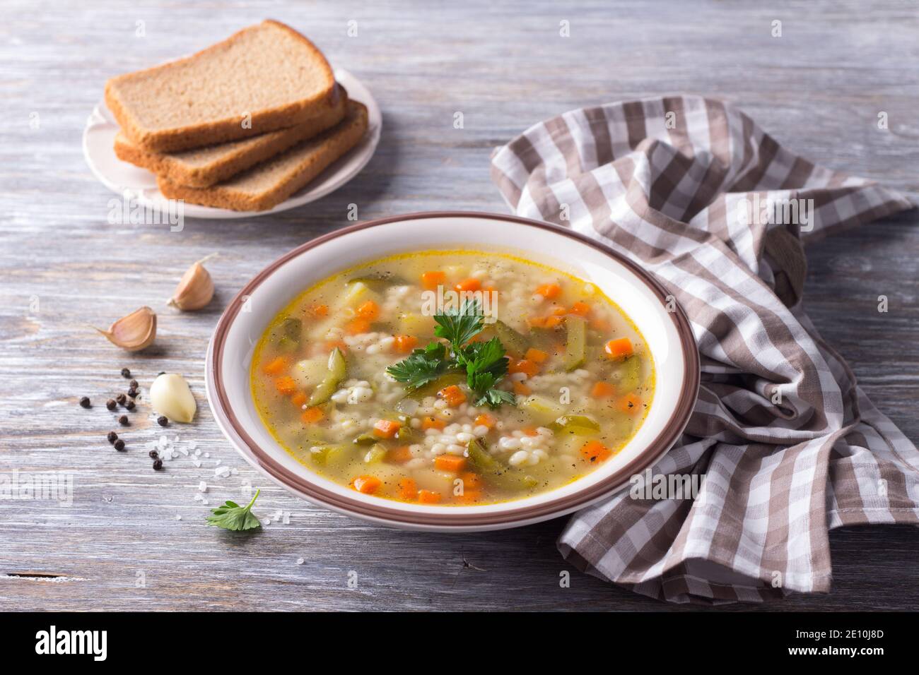 Zuppa vegana con cetrioli sottaceto e orzo perlato, rassolnik. Cucina tradizionale russa fatta in casa. Su un tavolo di legno Foto Stock