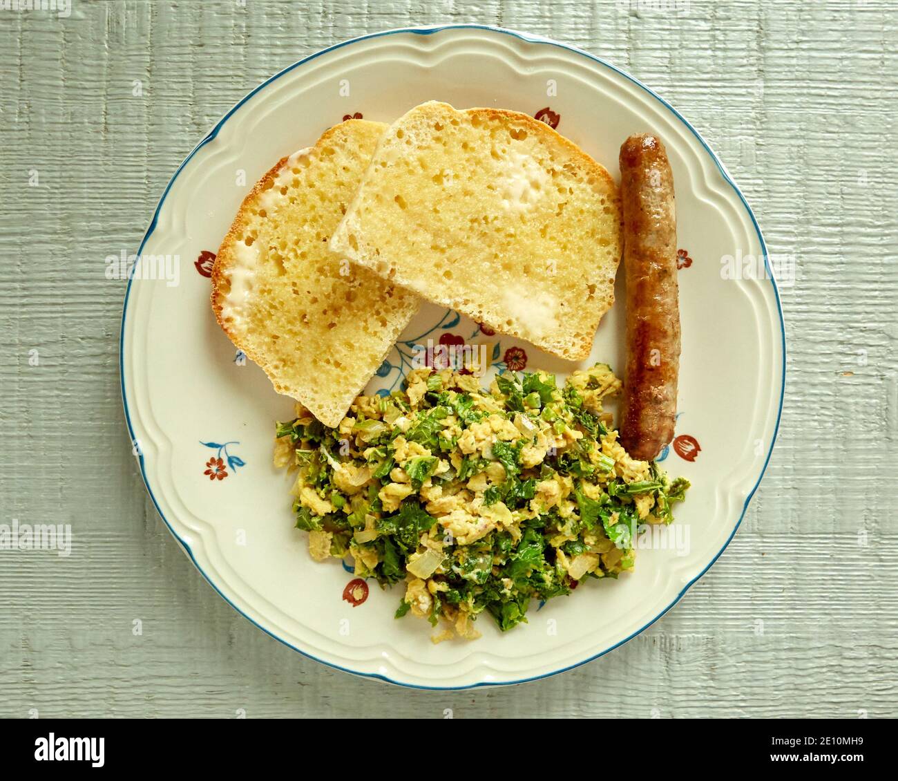 Vista panoramica del Kale e uova Scramble con pane tostato e salsiccia Su una piastra Foto Stock