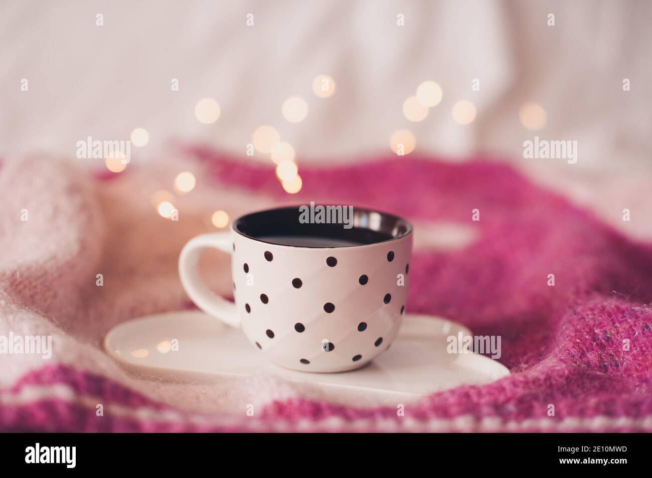 Tazza di caffè fresco sul vassoio sul pullover lavorato a maglia sopra le luci del ludovro primo piano. Buongiorno. Ora della colazione. Foto Stock