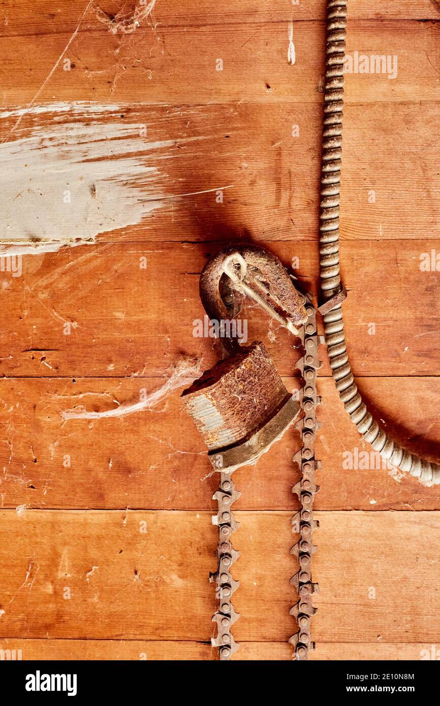 Vecchio lucchetto arrugginito con lame per motosega su parete in legno, vista verticale Foto Stock
