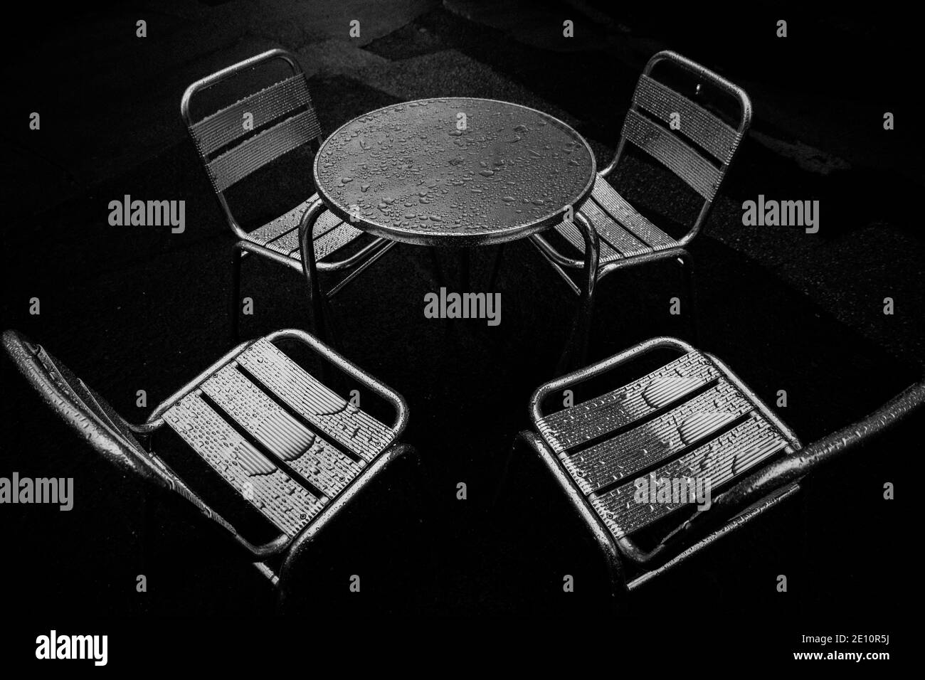 4 sedie da caffè in alluminio intorno a un tavolo dopo una pioggia doccia Foto Stock