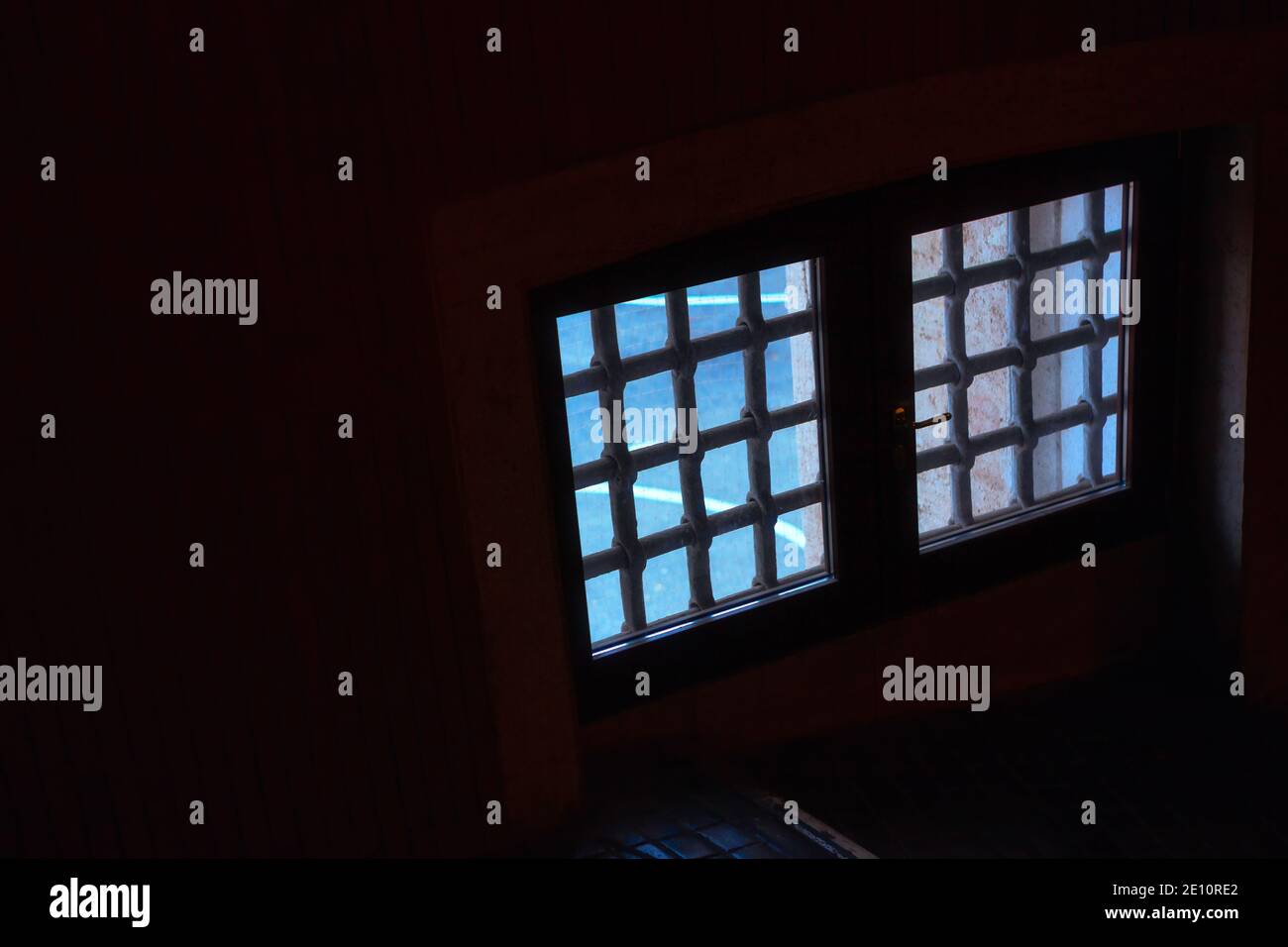 Vecchia finestra con barre . All'interno della camera oscura Foto Stock